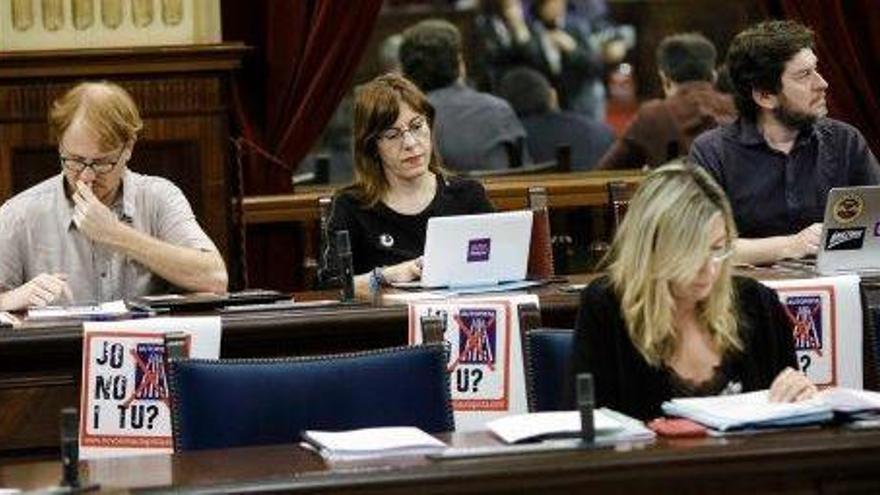 La bancada de Podemos exhibió ayer en el Parlament carteles con el símbolo del movimiento &#039;antiautopista&#039; de Ibiza.