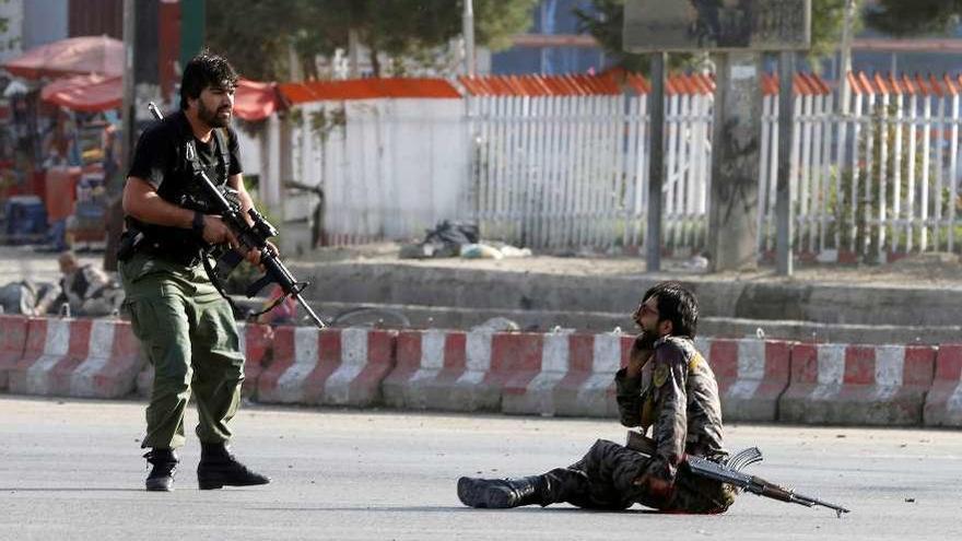 Un miembro de las fuerzas de seguridad afganas se acerca a un solado herido, ayer, en el ataque. // Reuters