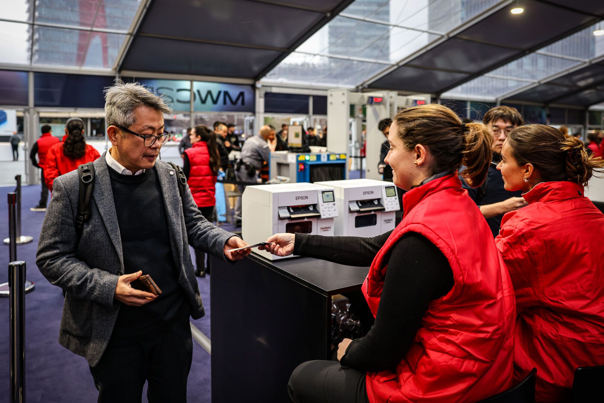 Un home ensenya la seva acreditació per entrar al Mobile World Congress 2025