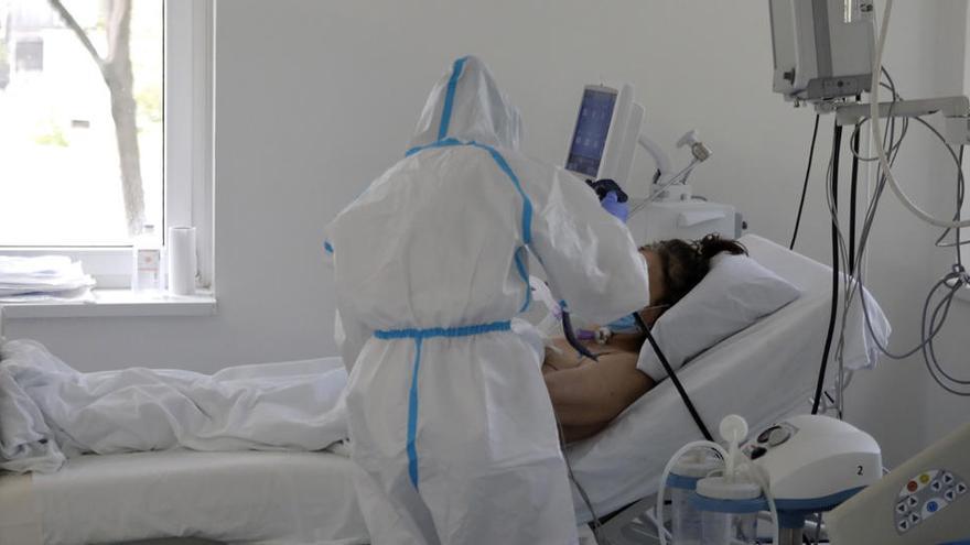 Un trabajador médico de cuidados intensivos atiende a un paciente en la UCI de un hospital en Belgrado.