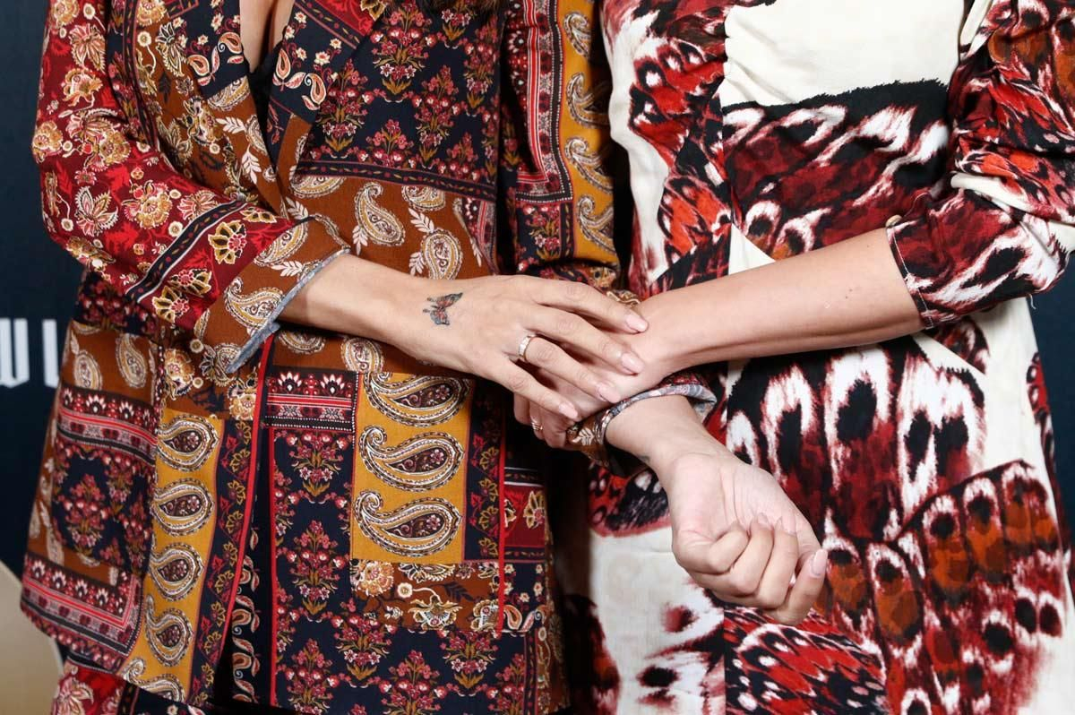 Las manos de Sara Carbonero, con tatuaje de mariposa, e Isabel Jiménez