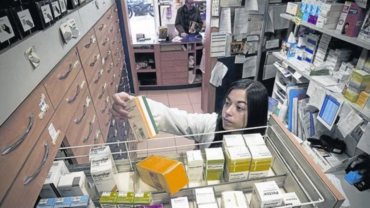 Una farmacéutica de Barcelona coge un medicamento de un cajón.
