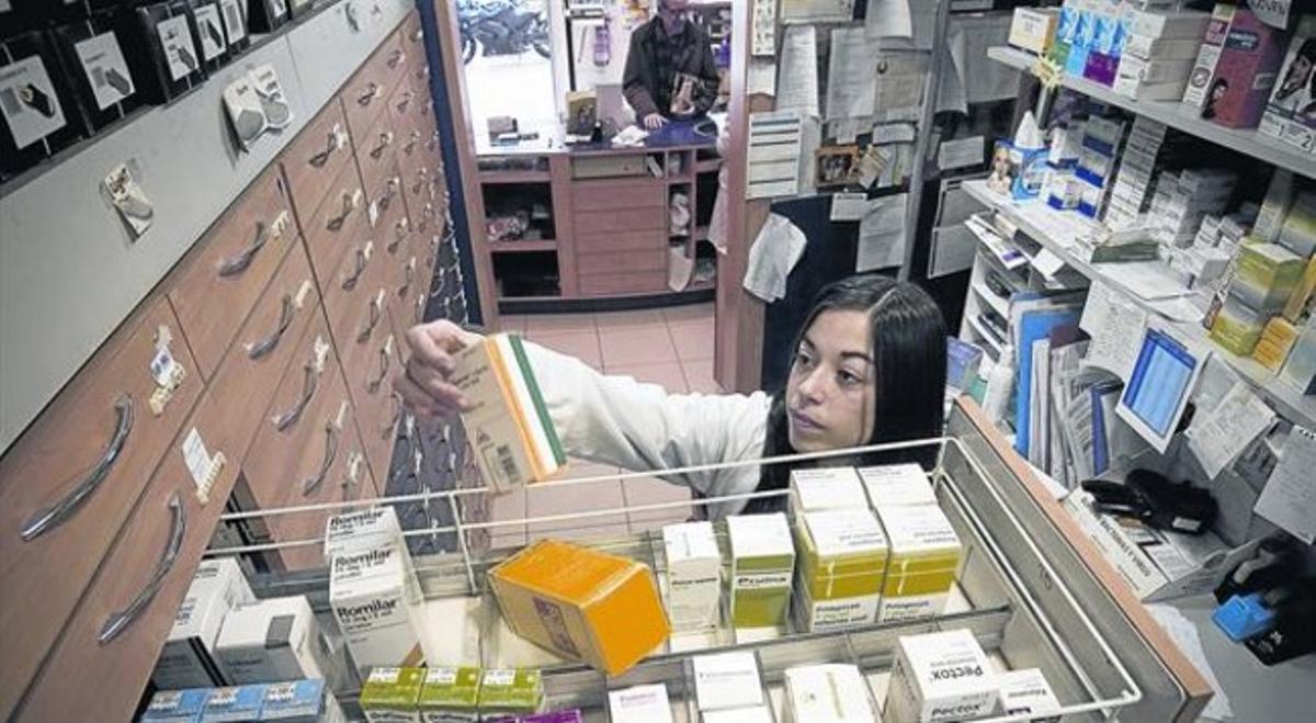 Una farmacèuticade Barcelona agafa un medicamentd’un calaix.