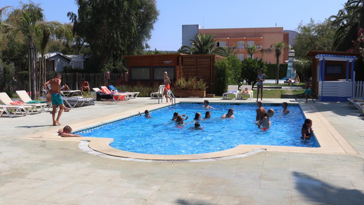 La piscina del càmping Salatà de Roses amb diversos turistes jugant a l&#039;aigua i d&#039;altres estirats a la tovallola el 29 de juliol de 2021