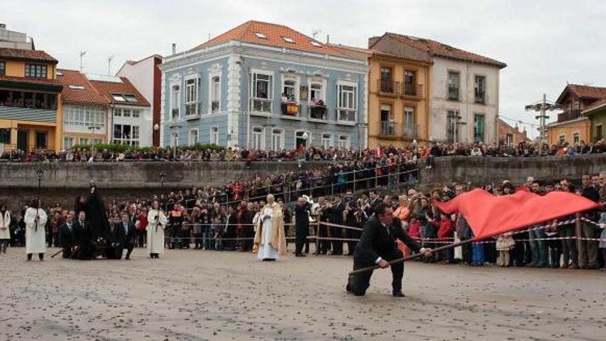 El abanderado de La Venia, César Menéndez, ondea el pendón de la Cofradía de Pescadores, con la Virgen aún enlutada en la playa de La Ribera.