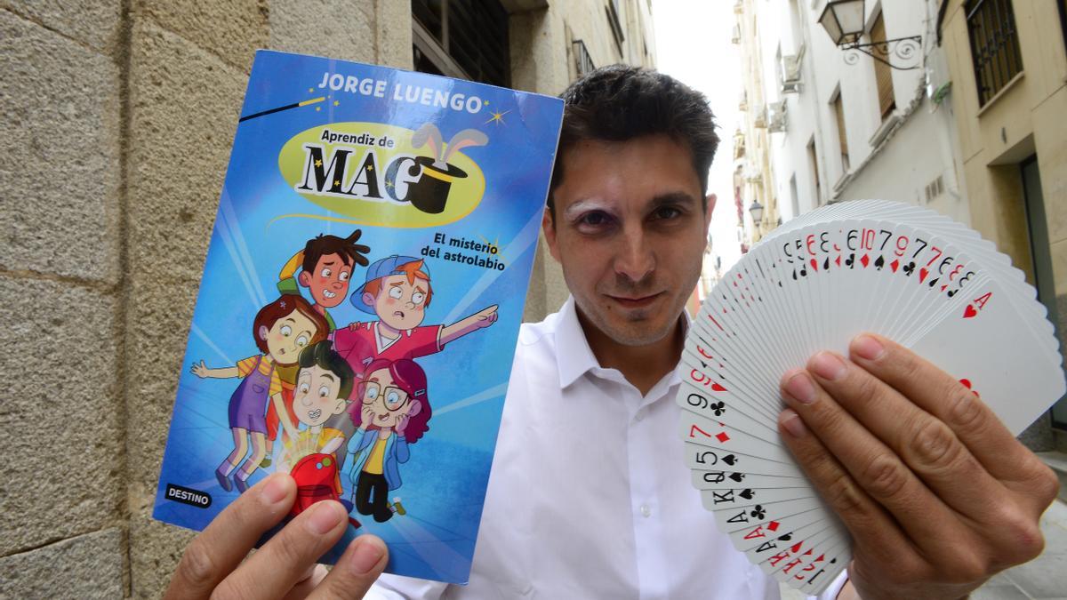 El mago y escritor cacereño Jorge Luengo posa con su nuevo libro y una baraja de cartas.