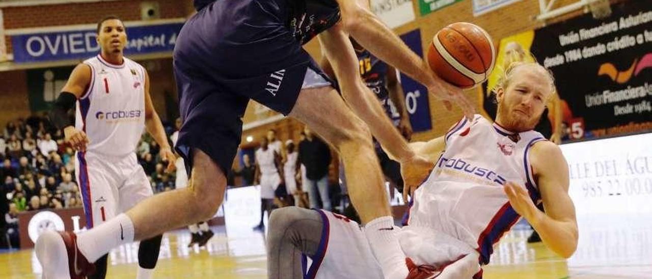 Tre&#039; Coggins, al fondo de la imagen, en un partido del Clavijo en el polideportivo de Pumarín. En primer término, Oliver Arteaga lucha por un balón con Gutenius.