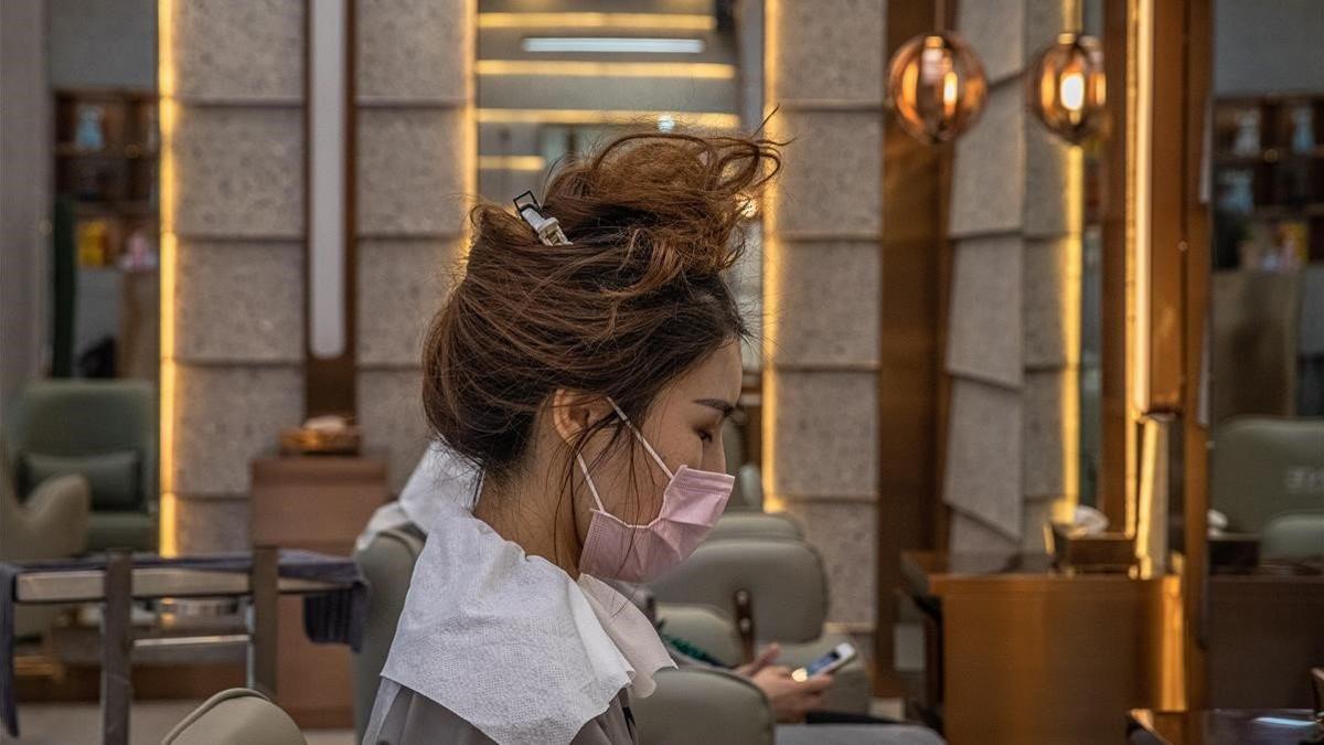 Una mujer se protege con una máscara en su visita a una peluquería de la ciudad china de Wuhan.