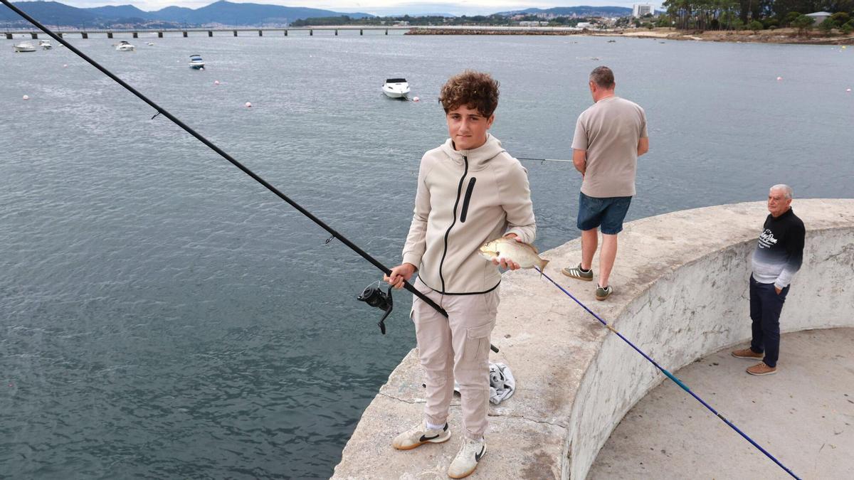 El joven Diego Viñas sujeta su caña y un ejemplar de dentón capturado este miércoles en la ría de Vigo. Se trata de un pez de aguas cálidas muy raro de ver en Galicia.