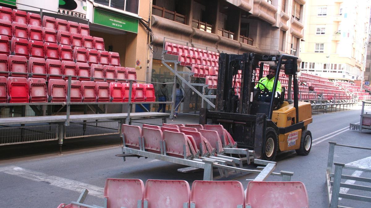 Una carretilla elevadora traslada los módulos de sillas de los palcos de Semana Santa de la carrera principal, este lunes.