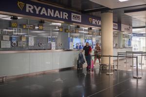 Archivo - Dos personas pasan junto a una ventanilla de Ryanair en el Aeropuerto Josep Tarradellas Barcelona-El Prat, a 8 de agosto de 2022, en Barcelona, Catalunya (España).