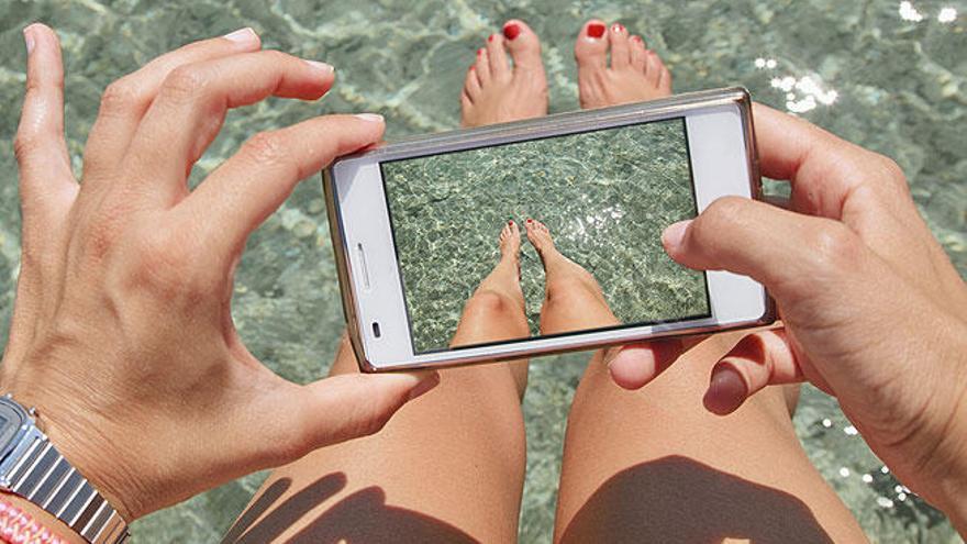 Una mujer se fotografía con su móvil en el agua.