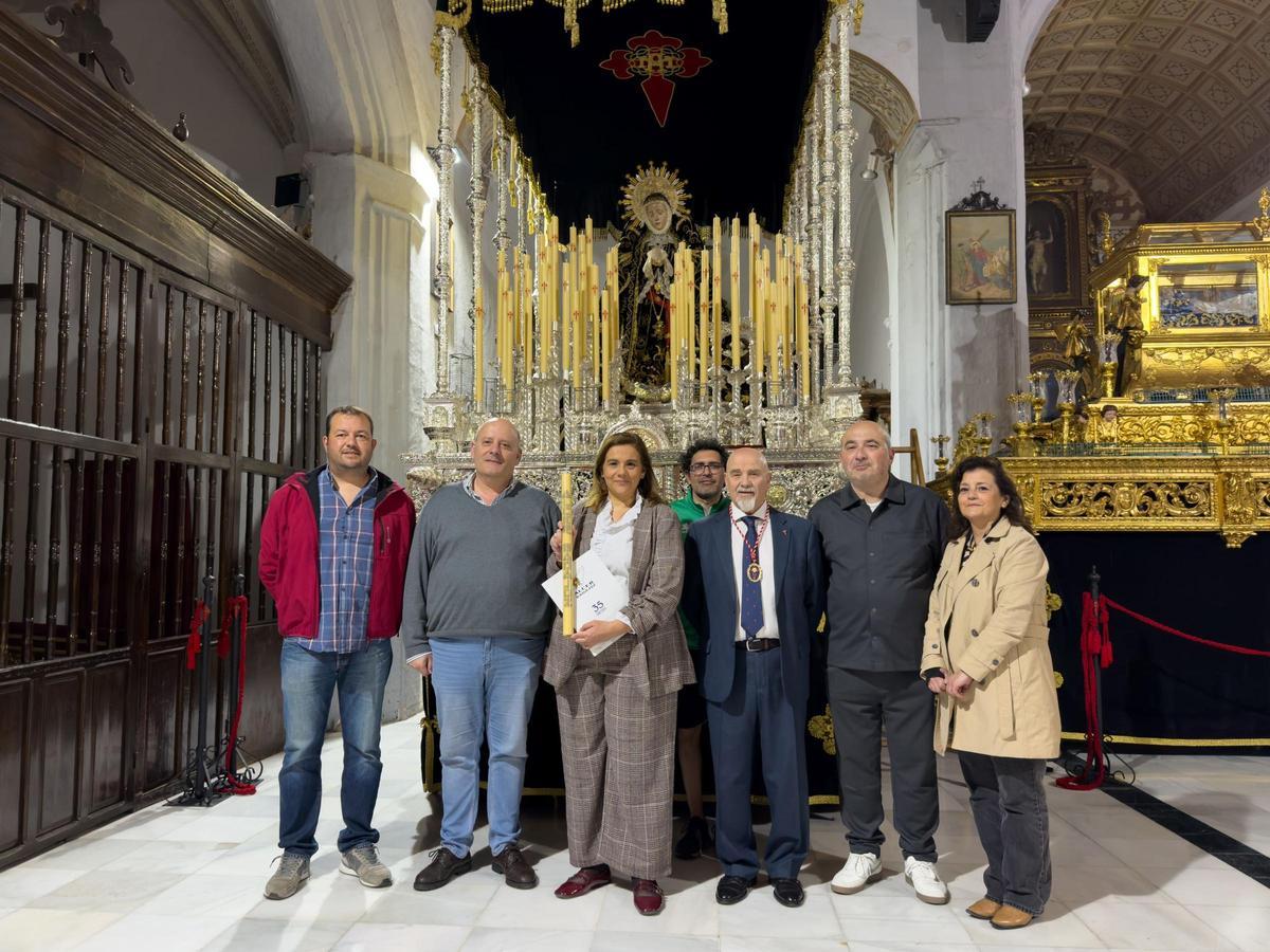 Miembros de la hermandad y de la asociación Alcer Badajoz posan con la vela que lleva su nombre ante el paso de la Virgen de las Lágrimas.