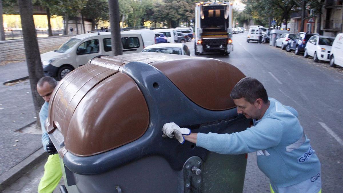 Dos operaris de la neteja posant a lloc un contenidor de fracció orgànica. | MARC MARTÍ /ARXIU