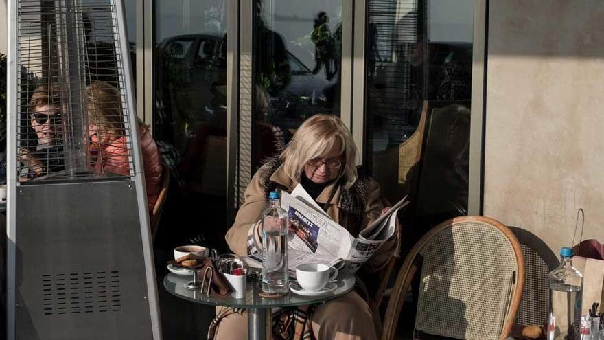 Un mujer lee el periódico en una terraza.