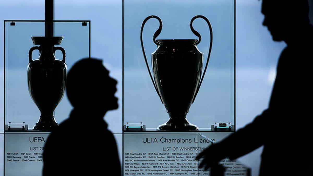 Dos hombres conversan junto a las copas de la Liga de Campeones y la Liga Europa, en la sede de la UEFA en Nyón (Suiza)