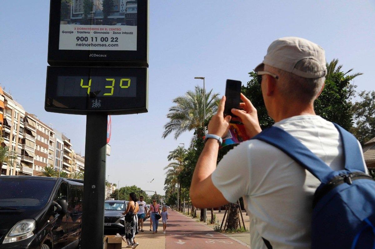 Un ciudadano toma una foto de la temperatura que marca un termómetro callejero de Córdoba.