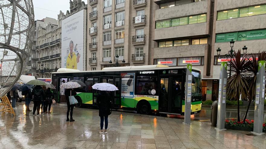 Usuarios de Vitrasa esperando en la Farola de Urzáiz, donde el Concello ha eliminado la marquesina para poner la bola gigante de Navidad.