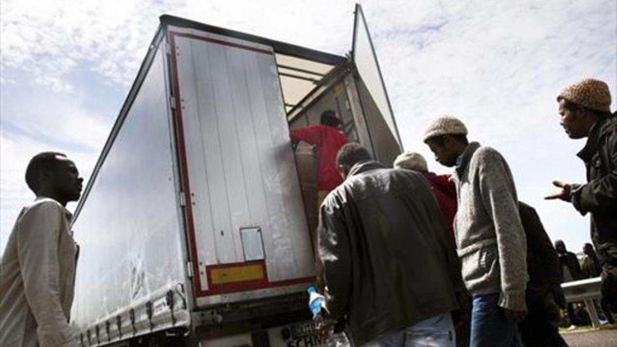 Inmigrantes suben a un camión en la localidad francesa de Calais para cruzar por el túnel al Reino Unido.