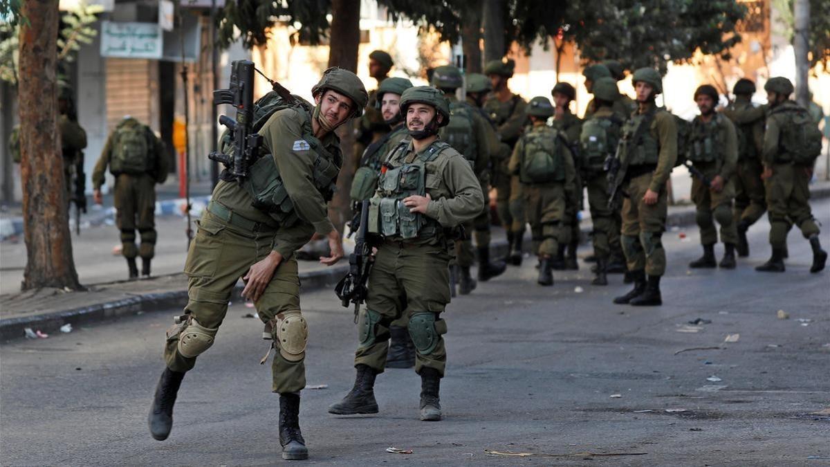 Un soldado israelí lanza un petardo contra un grupo de palestinos en Hebron durante un enfrentamiento, el pasado 13 de octubre.