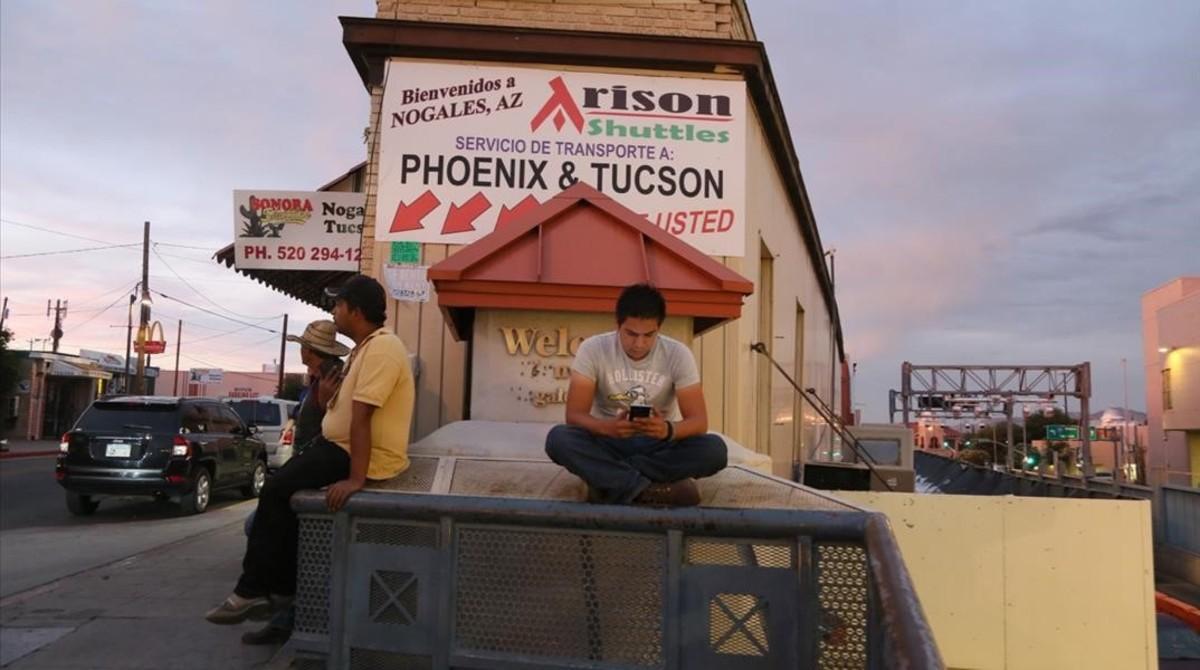 Varios hombres esperan junto a la parada de autobuses de Nogales (Arizona).