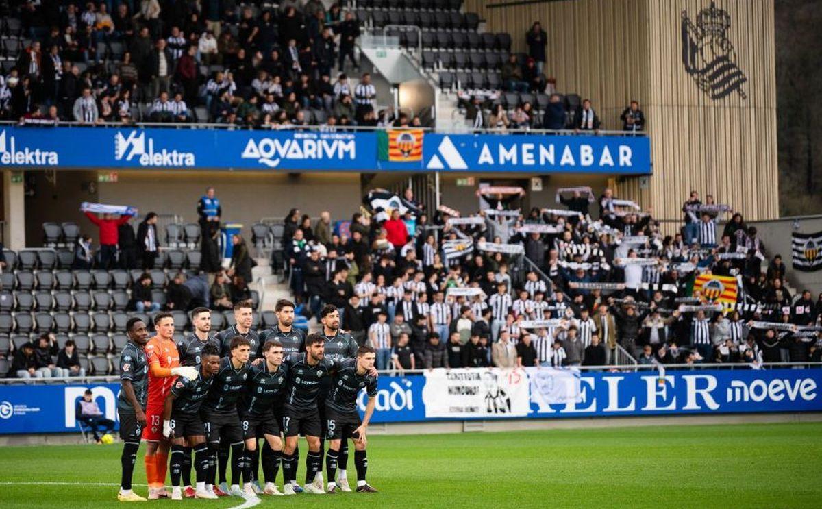 El once inicial del Castellón en el campo Z7 de Zubieta, con los decenas de aficionados 'orelluts' al fondo.