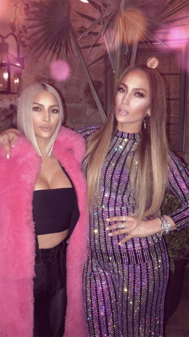 Kim Kardashian coon abrigo de pelo rosa y 'crop top' negro junto a Jennifer Lopez