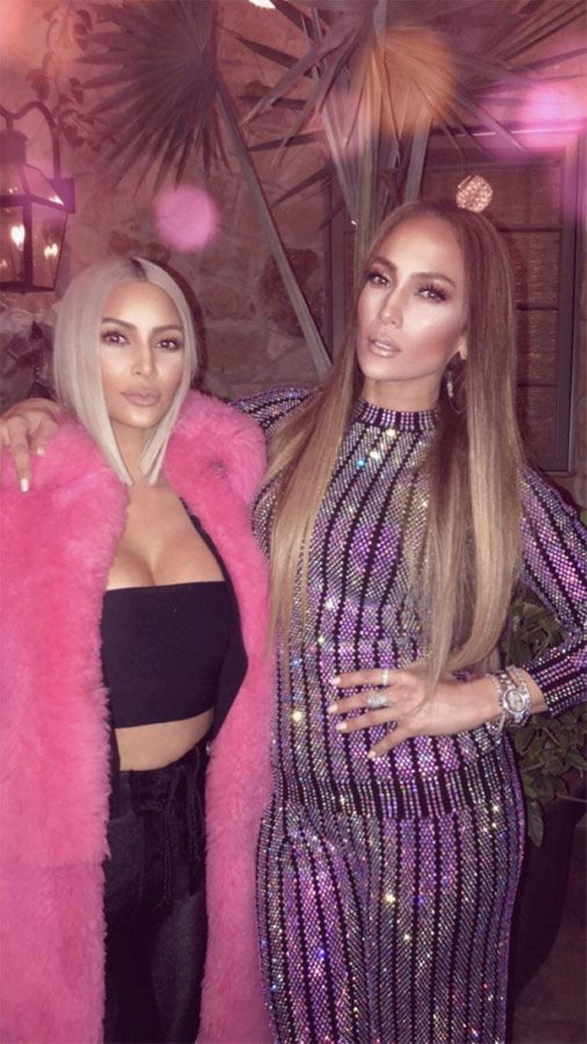 Kim Kardashian coon abrigo de pelo rosa y 'crop top' negro junto a Jennifer Lopez