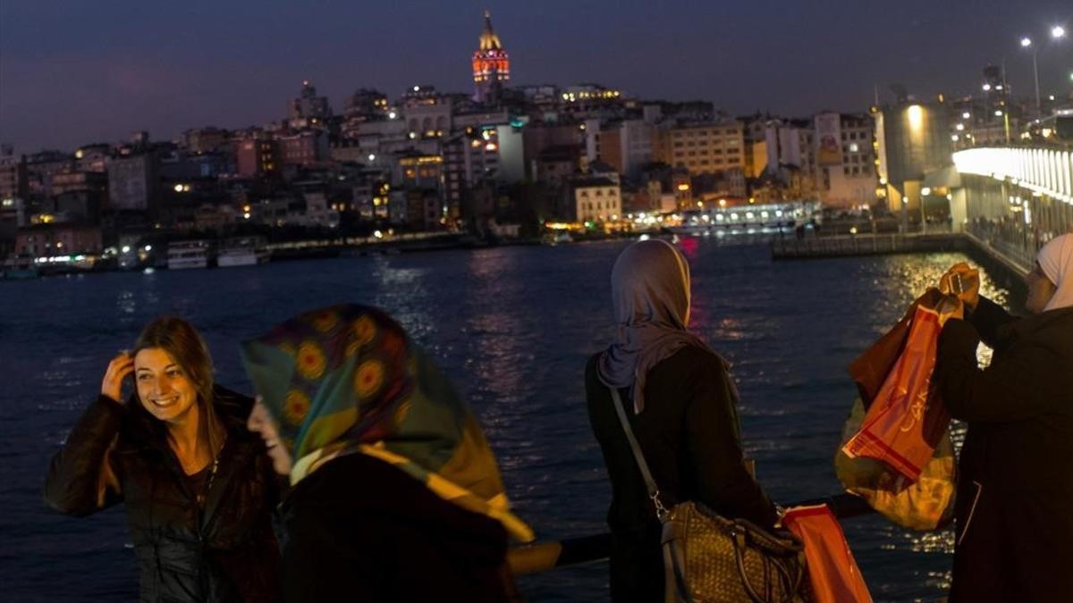 Varias mujeres con pañuelo y sin él fotografían el paisaje de Estambul desde el puente de Galata, el 23 de febrero.