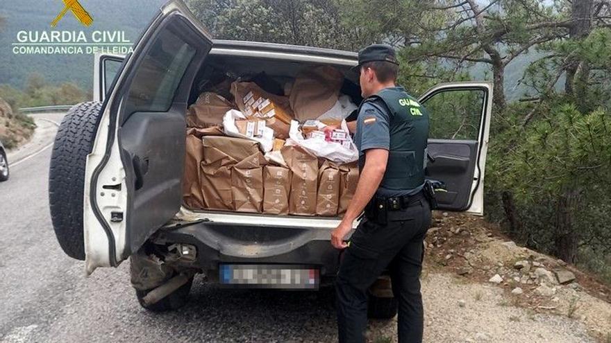 Un agent de la Guàrdia Civil mostra el maleter d'un totterreny on han trobat més de 5.300 paquets de tabac contraban