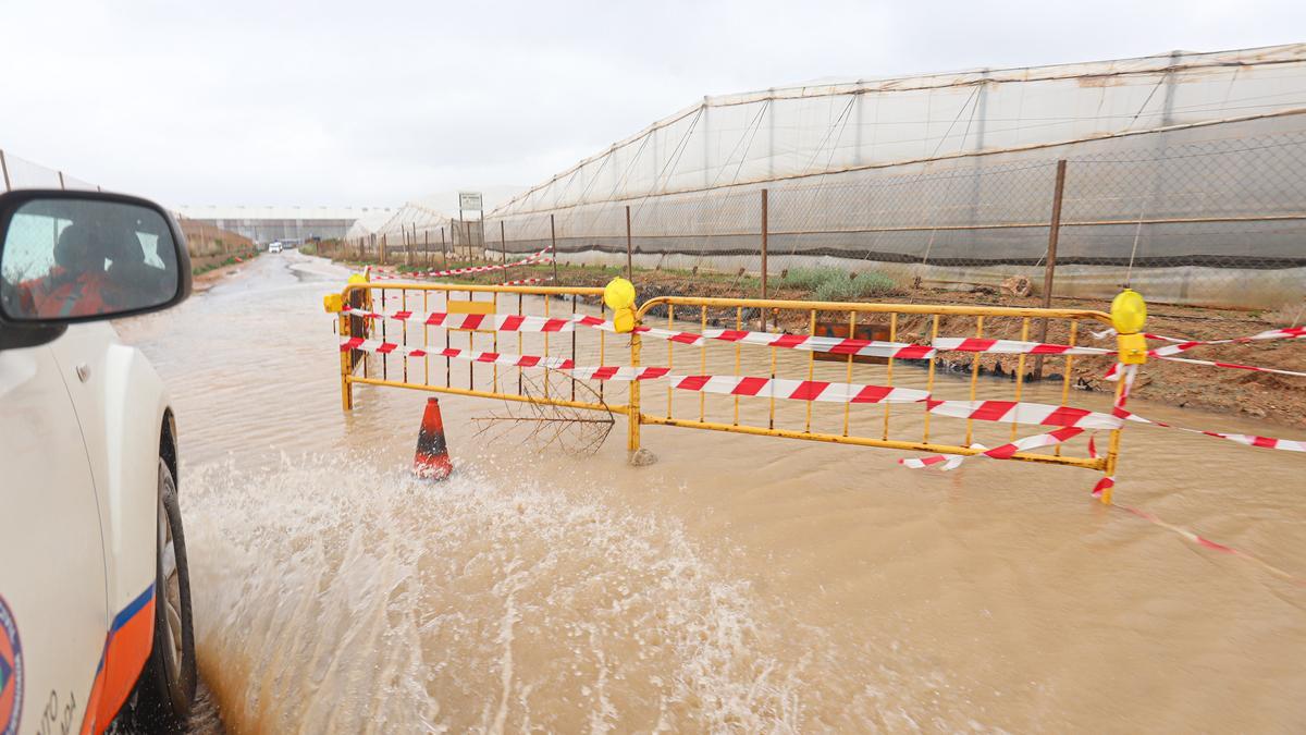 A la izquierda se observa un muro construido para evitar que las aguas corran por el bancal y se derivan  por el camino. Al fondo naves de una actividad industrial en San Pedro del Pinatar