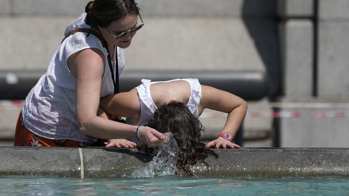 Una mujer se refresca en la fuente de Trafalgar Square, en Londres