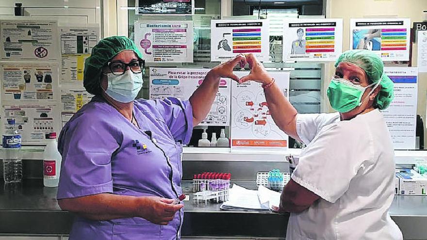 Dos sanitarias del Hospital General de La Palma dibujan un corazón con las manos.