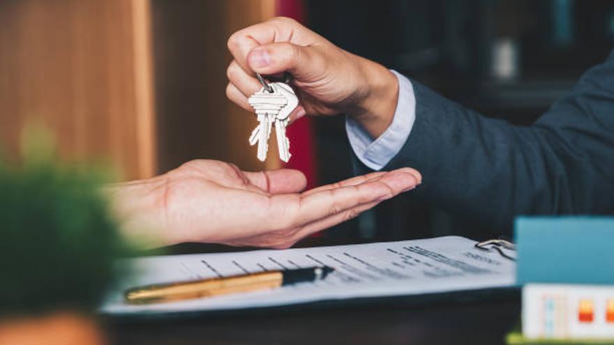 estate agent giving house keys to woman and sign agreement in office