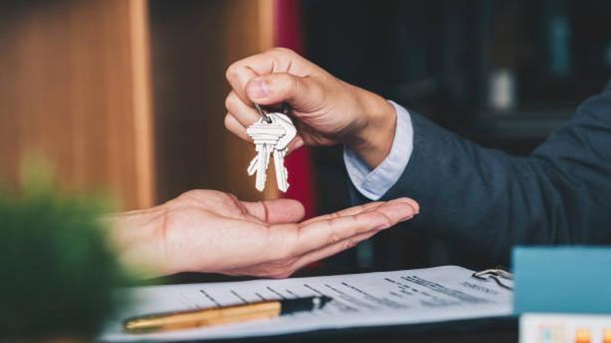 estate agent giving house keys to woman and sign agreement in office