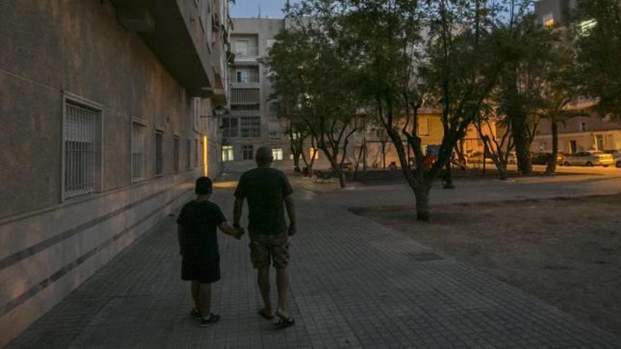 Un vecino de la zona pasea junto a su hijo al caer la noche, con el parque a oscuras al fondo.