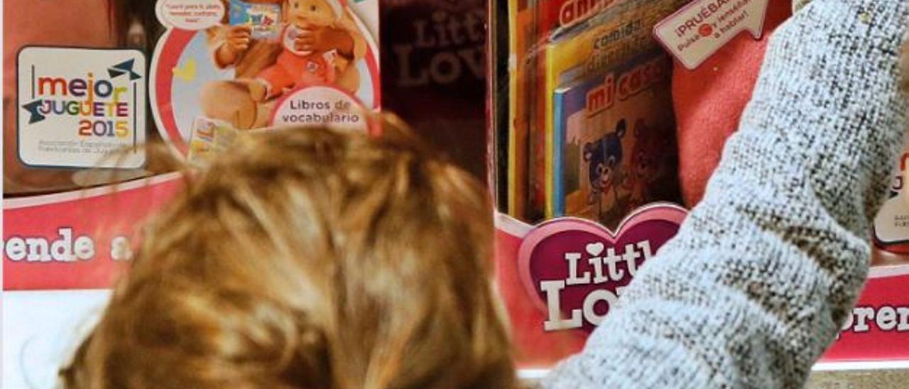 Una niña inspecciona una muñeca en una tienda de juguetes de València. | EFE
