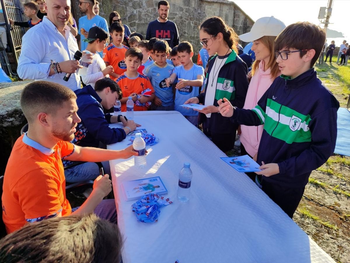 El futbolista Sergio Carreira, del primer equipo del Celta; el central Pablo Meixús, del Celta Fortuna; y Nuria Gómez, de As Celtas, firman ayer autógrafos en Cela a los más jóvenes.