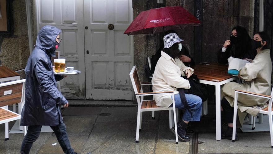 Una camarera lleva varias cervezas a una de las mesas de la terraza de su establecimiento.