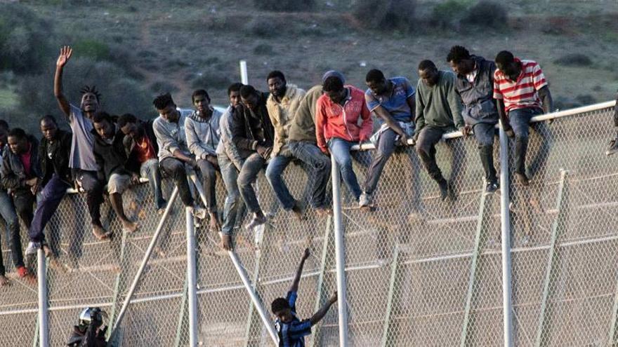 Un grupo de inmigrantes encaramado a la valla de Melilla.