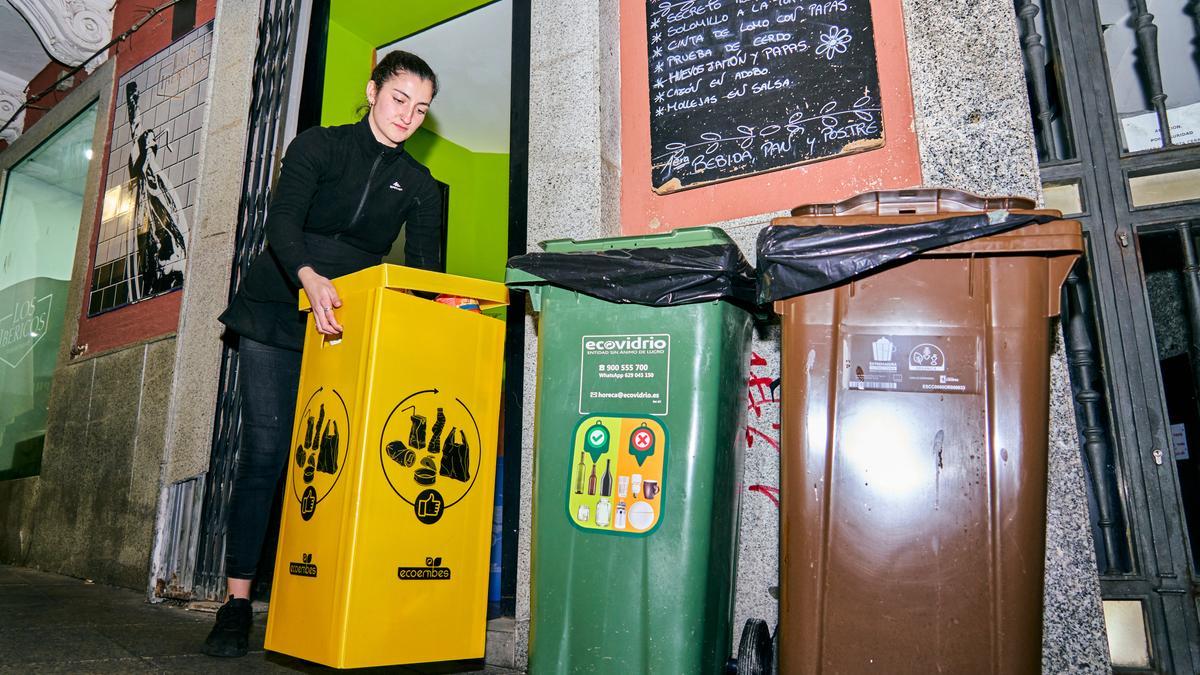 Una joven deposita uno de los contenedores en la calle en una foto de archivo.