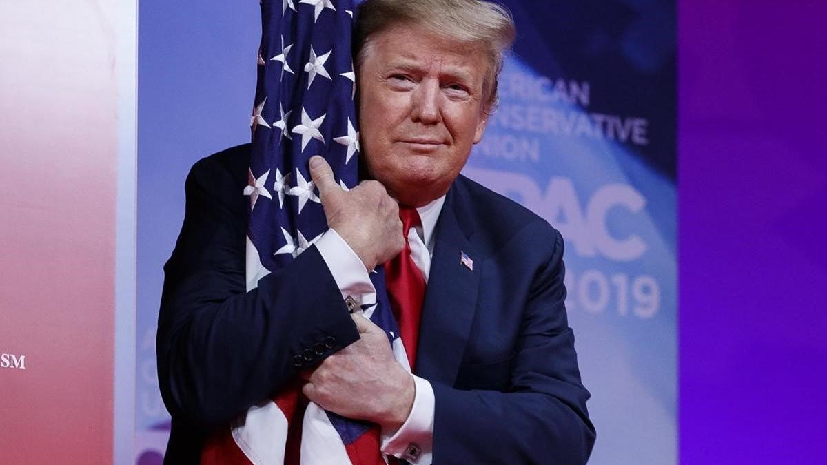 El presidente Donald Trump abraza la bandera de Estados Unidos en la Conferencia de Acción Política Conservadora.