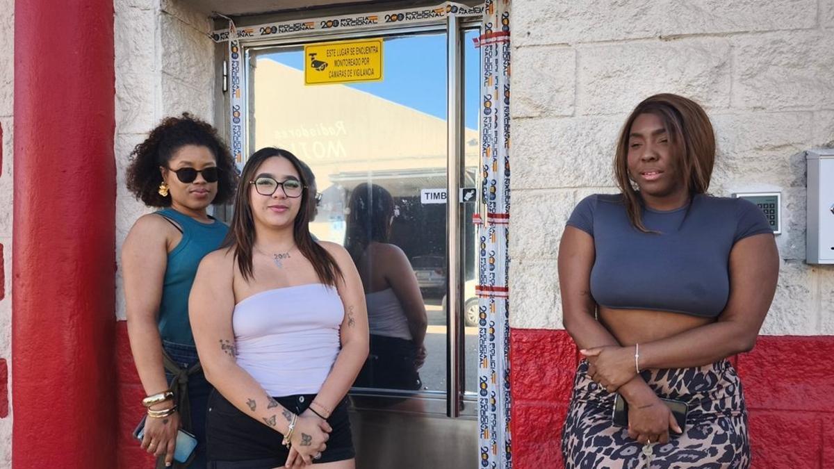 Karina, Mayarí y Lulú, tres de las mujeres que quedaron atrapadas tras el precinto policial de un club de alterne en Jaén donde ejercían la prostitución, a las puertas del local con el precinto policial.