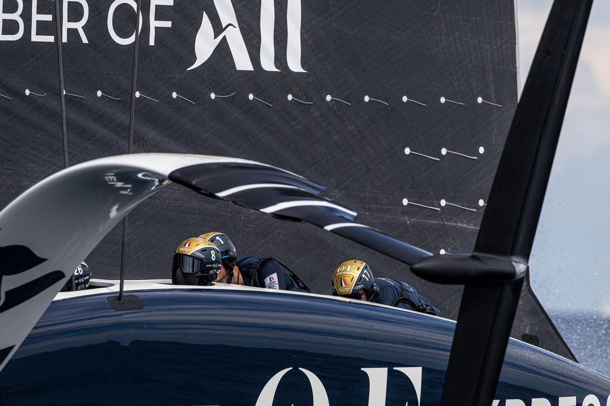 El AC75 del equipo francés Orient Express Racing Team, con los ciclistas en pleno trabajo en una de las regatas de la Louis Vuitton Cup.