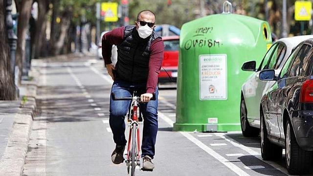 Un ciclista con mascarilla desplazándose ayer por València para acudir al trabajo.