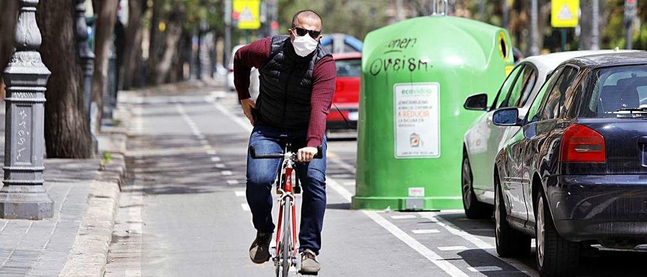 Un ciclista con mascarilla desplazándose ayer por València para acudir al trabajo.