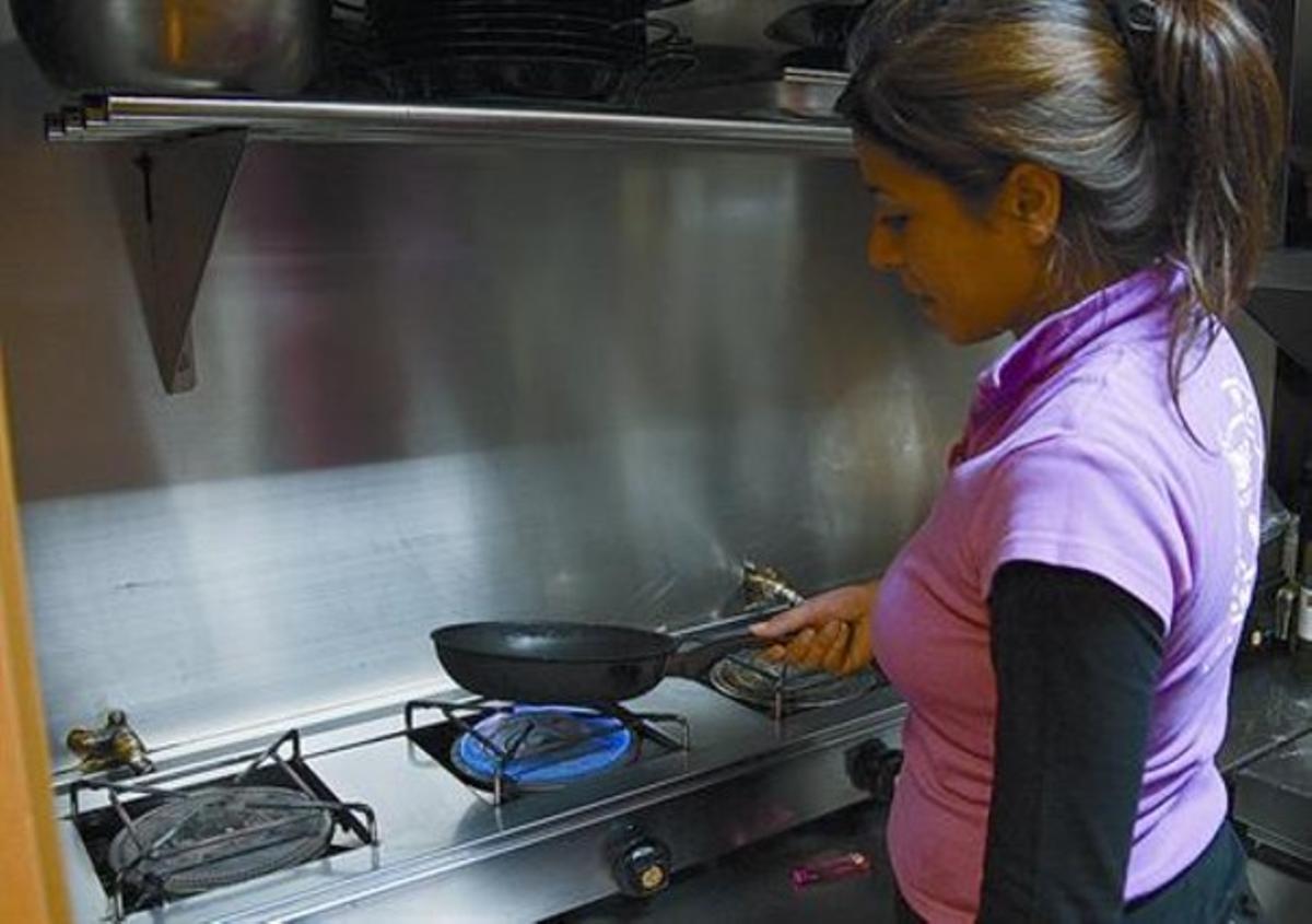 Una noia prepara el dinar en una cuina.