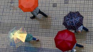 Gente protegiéndose con paraguas en un día de lluvia