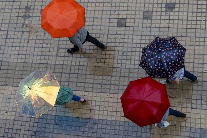 Gente protegiéndose con paraguas en un día de lluvia