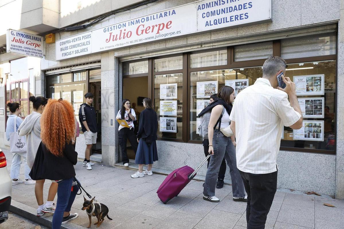 Varios jóvenes en la entrada de una inmobiliaria situada en la capital gallega